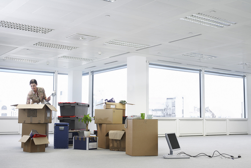 Young,Businesswoman,Unpacking,Cartons,In,An,Empty,Office,Space